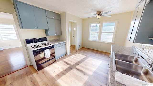 kitchen featuring ceiling fan, light hardwood / wood-style floors, white gas range, and sink