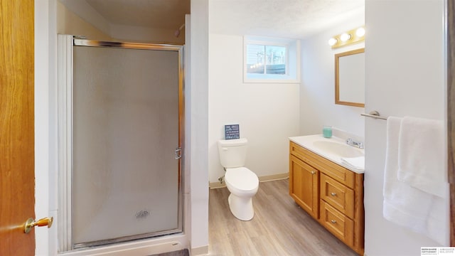 bathroom featuring vanity, a shower with door, toilet, a textured ceiling, and wood-type flooring