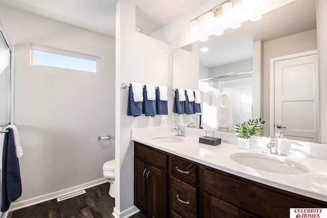 bathroom with hardwood / wood-style floors, vanity, toilet, and a shower with shower door