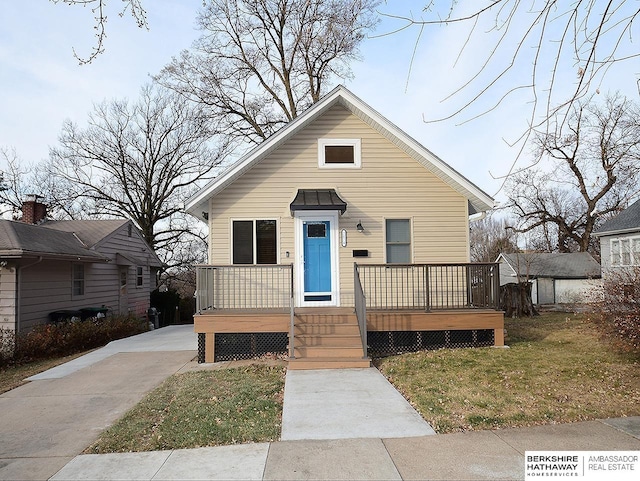 bungalow featuring a wooden deck and a front lawn