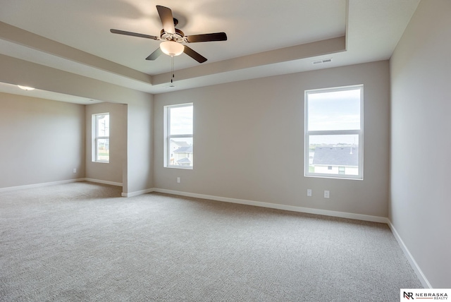 carpeted spare room featuring a raised ceiling and ceiling fan