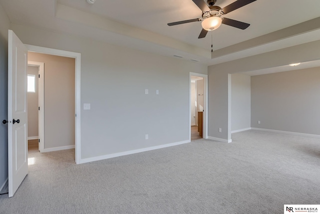 carpeted spare room featuring ceiling fan and a tray ceiling