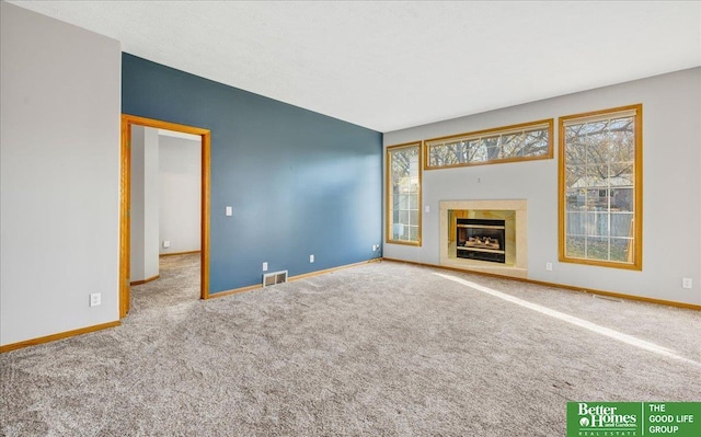 unfurnished living room with carpet floors and a tiled fireplace