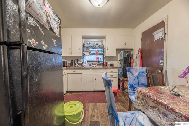 kitchen featuring black refrigerator, white cabinets, dark wood-type flooring, and sink