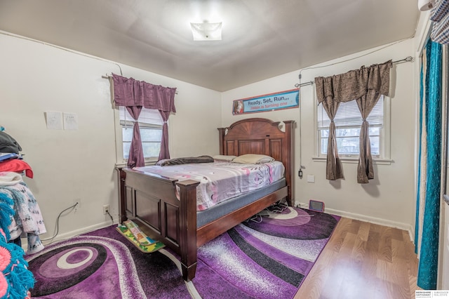 bedroom with multiple windows and hardwood / wood-style flooring