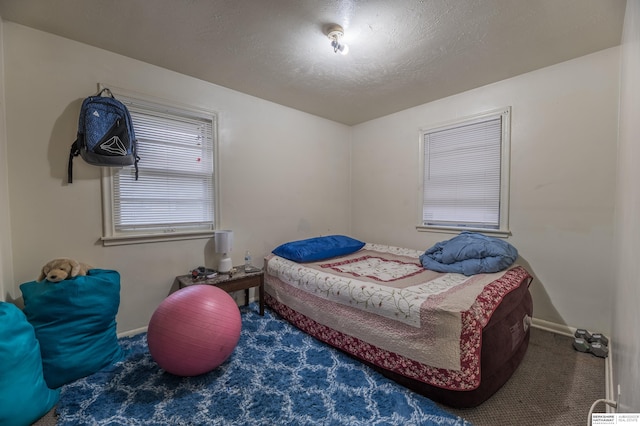 bedroom with dark colored carpet and a textured ceiling