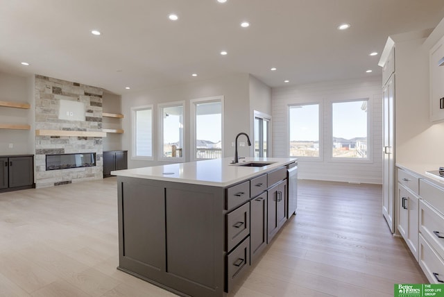 kitchen featuring white cabinets, a stone fireplace, plenty of natural light, and sink