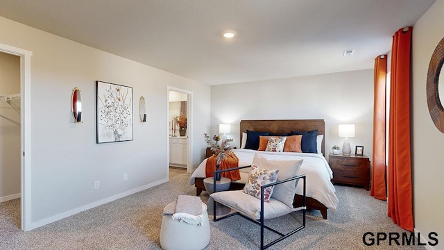 bedroom with ensuite bath, a spacious closet, and light colored carpet