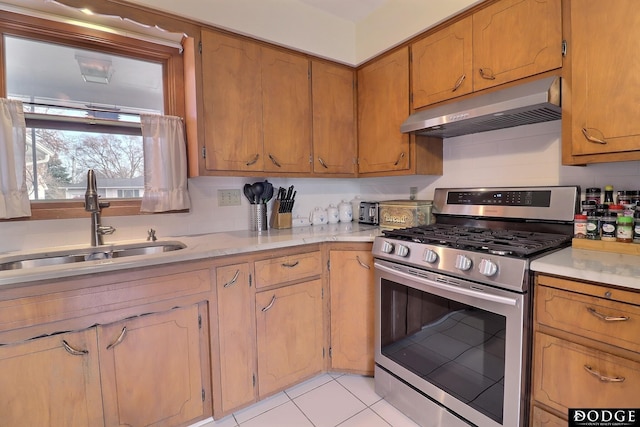 kitchen with light tile patterned floors, stainless steel gas stove, and sink