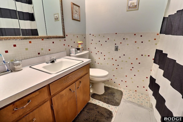 bathroom featuring tile patterned flooring, vanity, toilet, and tile walls