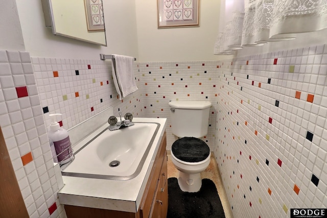 bathroom with vanity, toilet, and tile walls