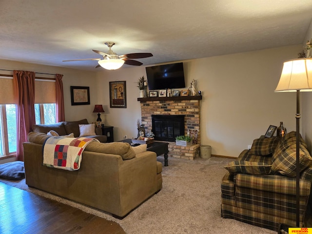 living room with hardwood / wood-style floors, ceiling fan, a textured ceiling, and a brick fireplace