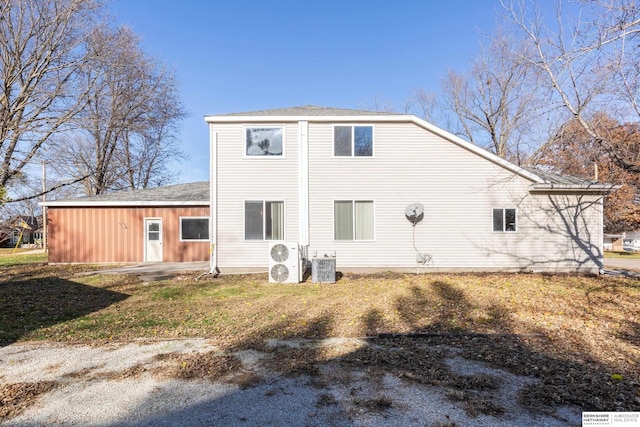 rear view of house with central AC unit and a lawn