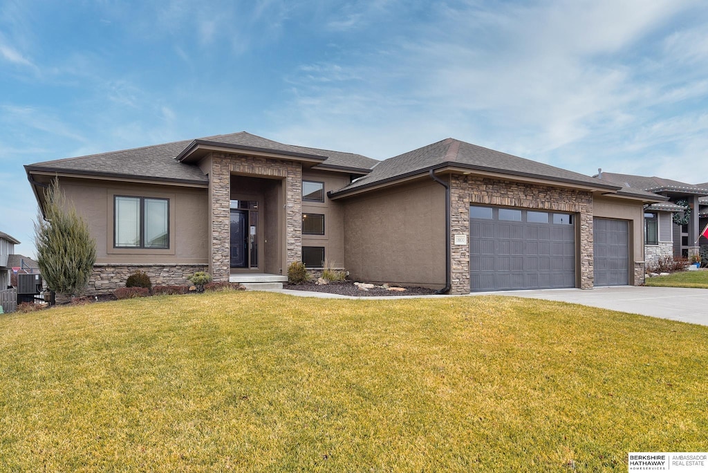 prairie-style house featuring a garage, a front lawn, and cooling unit