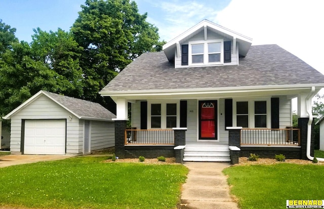 view of front of house featuring a porch, a garage, an outbuilding, and a front lawn