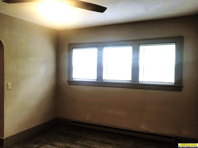 empty room with ceiling fan, dark wood-type flooring, and a baseboard heating unit