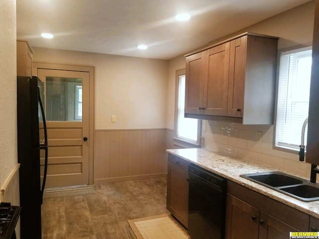 kitchen featuring black appliances, a healthy amount of sunlight, light stone countertops, and light hardwood / wood-style flooring