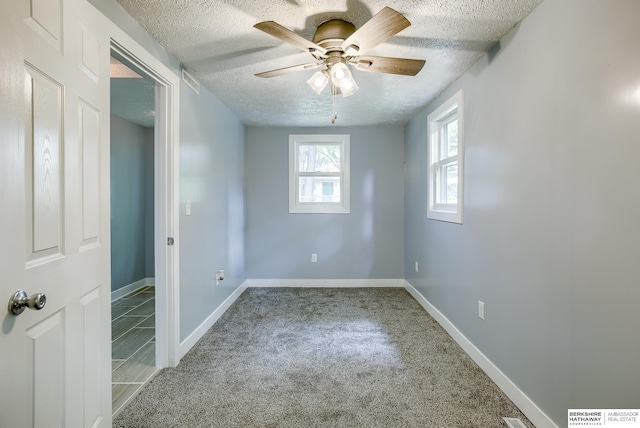 carpeted spare room featuring ceiling fan and a textured ceiling