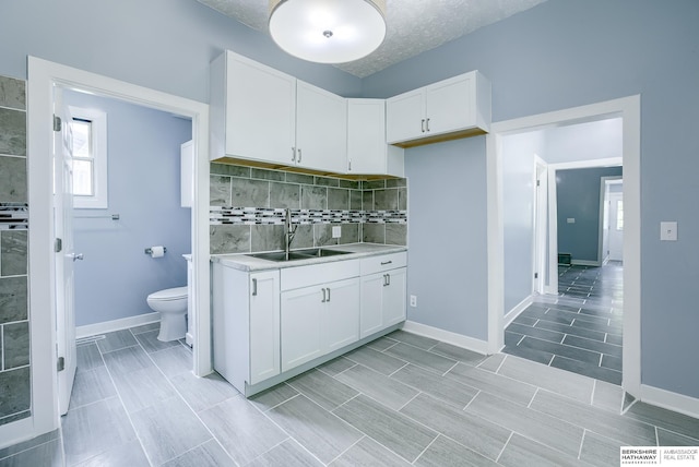 kitchen with tasteful backsplash, sink, white cabinets, and a textured ceiling