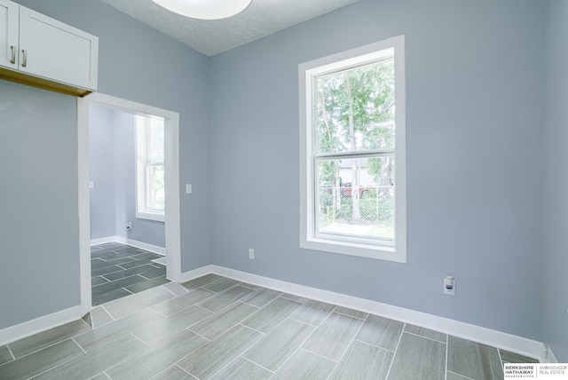 unfurnished room featuring a textured ceiling and a wealth of natural light