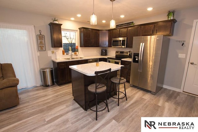 kitchen with pendant lighting, light hardwood / wood-style flooring, appliances with stainless steel finishes, a center island, and dark brown cabinetry