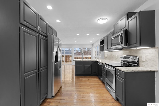 kitchen featuring backsplash, light hardwood / wood-style floors, stainless steel appliances, sink, and gray cabinets