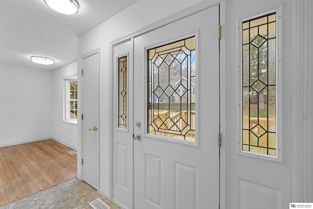 entrance foyer with a textured ceiling, light wood-type flooring, and plenty of natural light