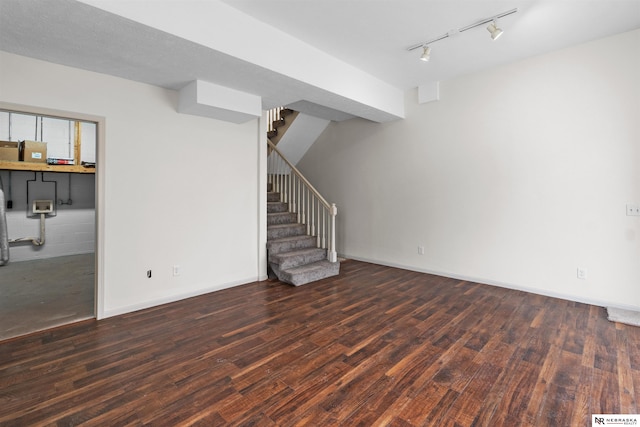 basement featuring rail lighting and dark hardwood / wood-style floors