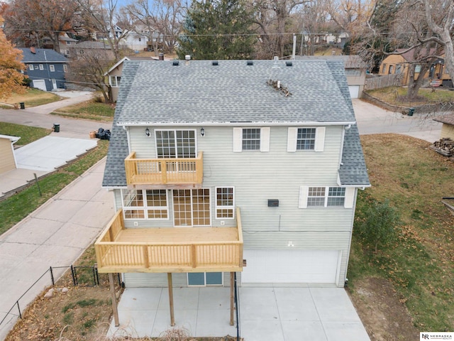 rear view of property featuring a balcony and a garage