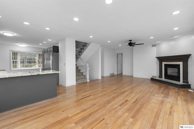 unfurnished living room featuring ceiling fan, sink, and light hardwood / wood-style floors