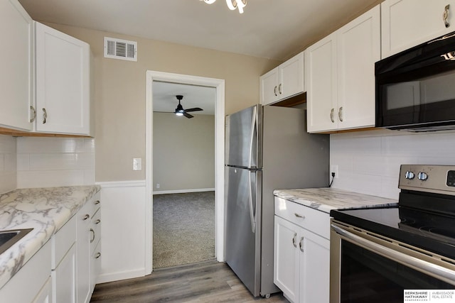 kitchen featuring white cabinets, light stone countertops, light wood-type flooring, and stainless steel appliances