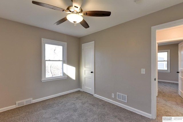 carpeted spare room featuring a wealth of natural light and ceiling fan