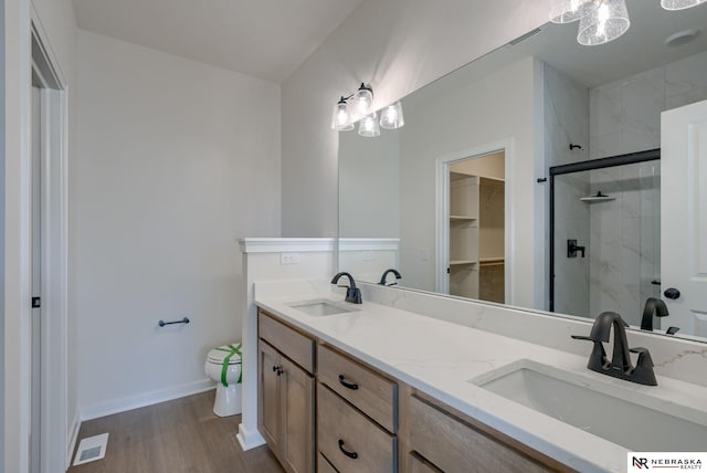 full bathroom with a sink, a shower stall, toilet, and wood finished floors