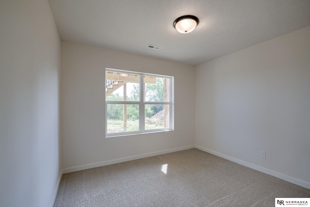 carpeted empty room featuring baseboards and visible vents