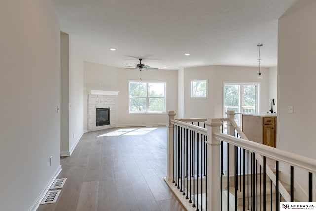 hallway with a wealth of natural light, baseboards, visible vents, and wood finished floors