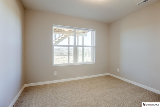 unfurnished room with carpet floors, visible vents, and baseboards