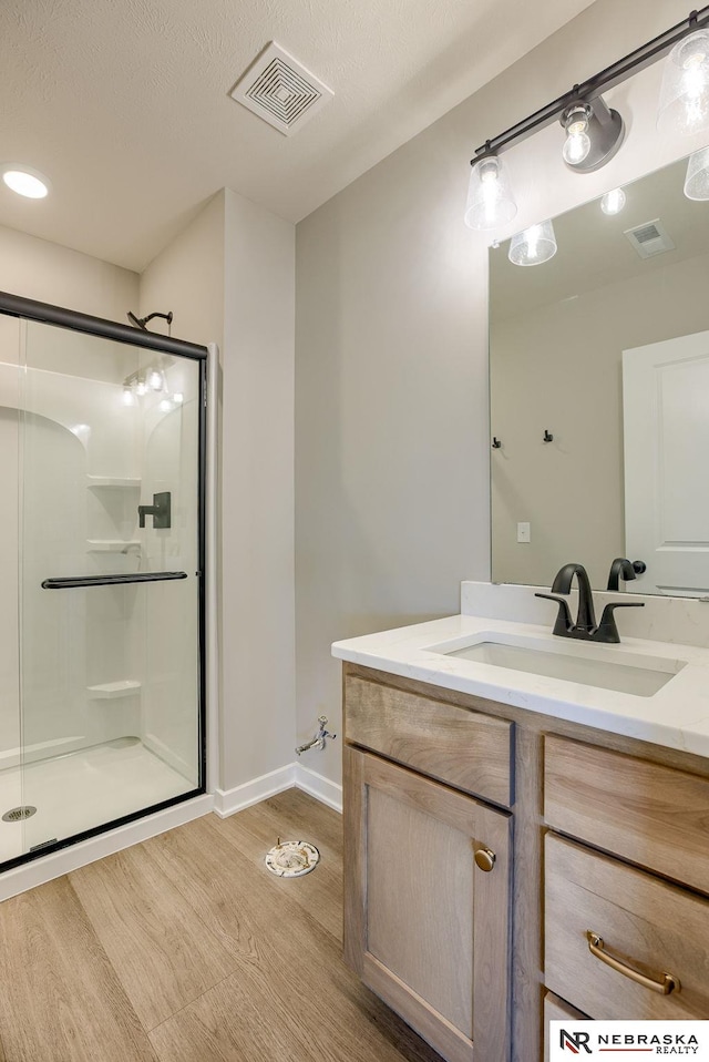 full bathroom with visible vents, a shower stall, and wood finished floors