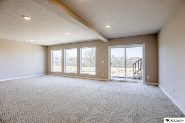 carpeted spare room featuring beamed ceiling, a textured ceiling, and baseboards