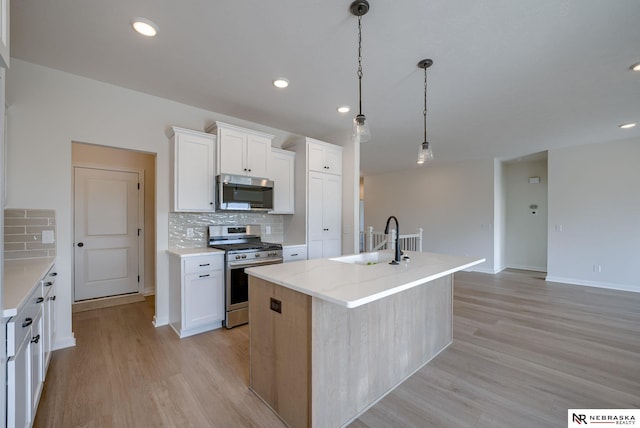 kitchen with stainless steel appliances, backsplash, a sink, and light wood-style floors