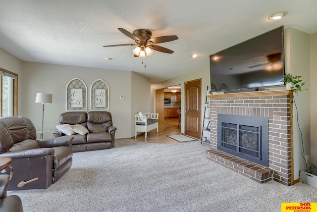 carpeted living room featuring a textured ceiling, a brick fireplace, and ceiling fan