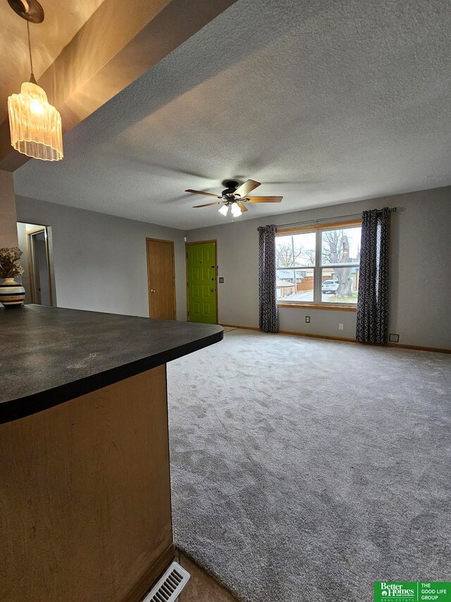 unfurnished living room featuring carpet, a textured ceiling, and ceiling fan