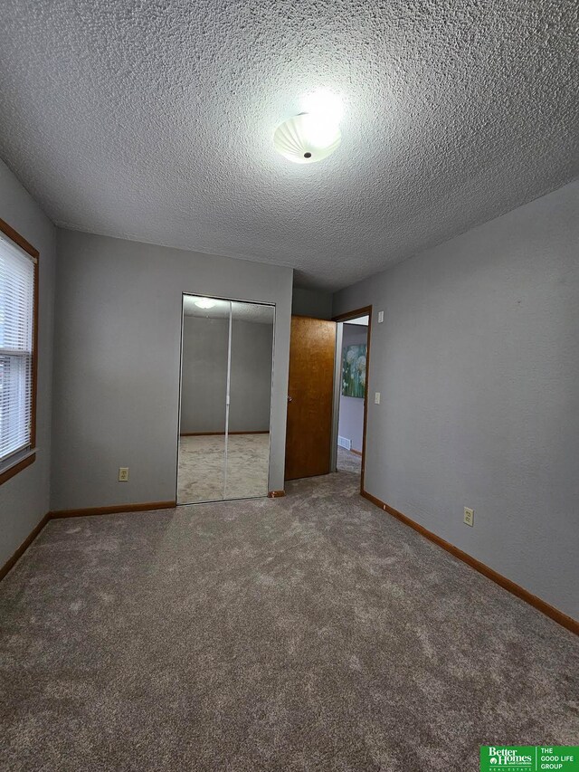 unfurnished bedroom featuring a textured ceiling, light colored carpet, and a closet