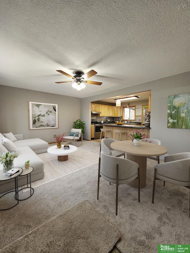 carpeted living room featuring ceiling fan and a textured ceiling