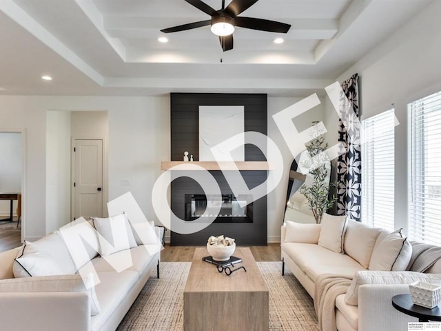 living room with ceiling fan, a tray ceiling, and light hardwood / wood-style flooring