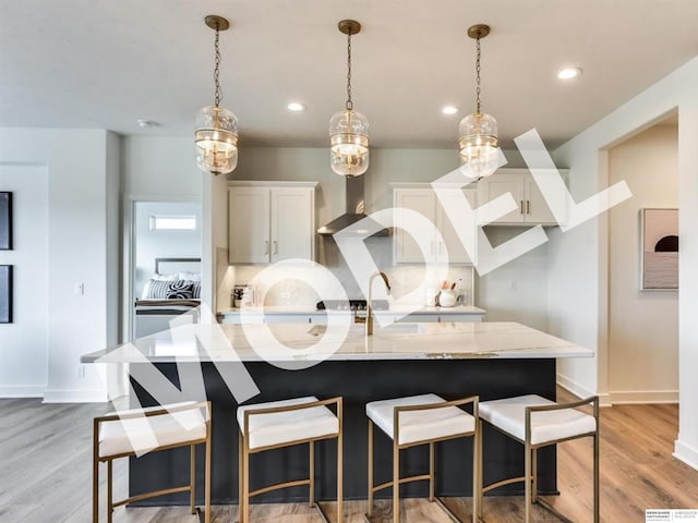 kitchen featuring white cabinets, a large island, hanging light fixtures, and light hardwood / wood-style flooring