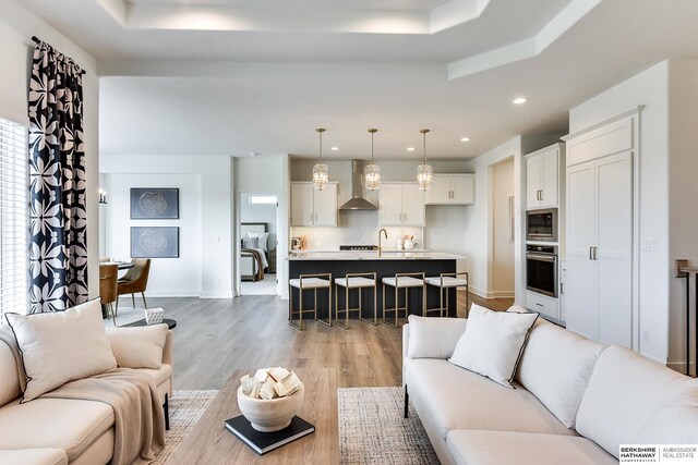 6614 S 200th Ave, Omaha, NE 68135 - kitchen with a center island with sink, light wood finished floors, wall chimney exhaust hood, white cabinets, and recessed lighting
