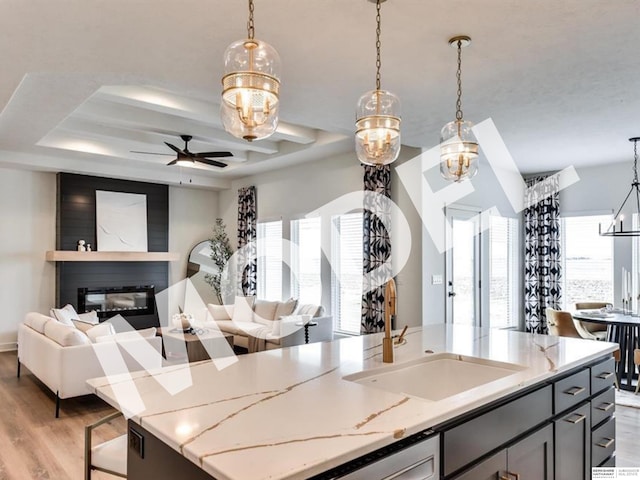 kitchen with a wealth of natural light, light stone counters, and hanging light fixtures