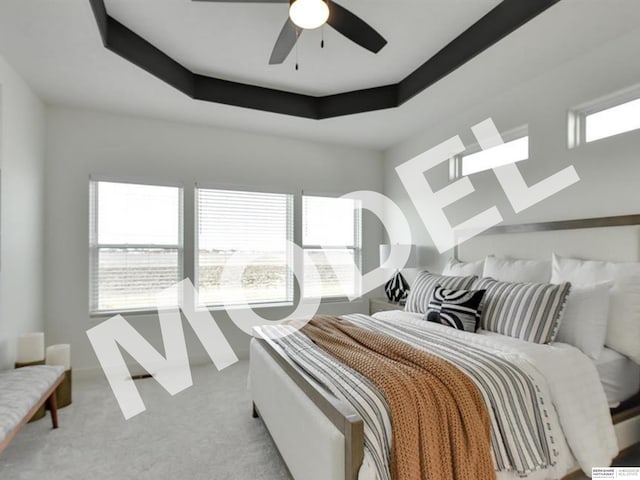 carpeted bedroom featuring ceiling fan, a raised ceiling, and multiple windows