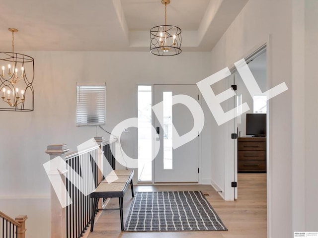 entryway featuring an inviting chandelier, light hardwood / wood-style flooring, and a tray ceiling