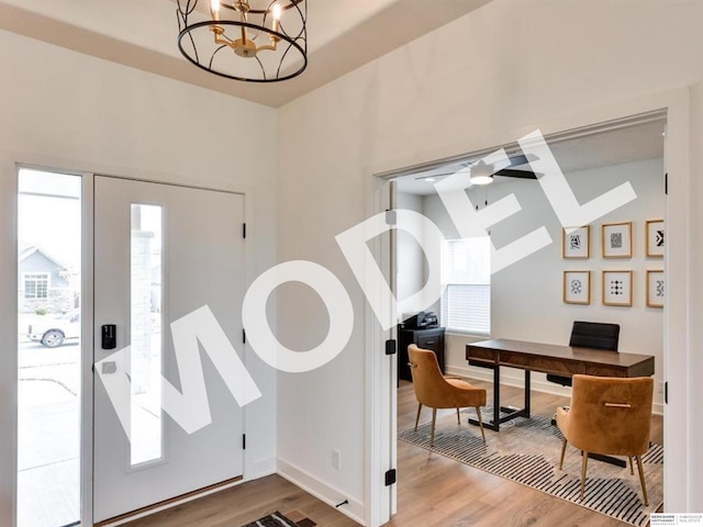 entryway with ceiling fan with notable chandelier and light wood-type flooring